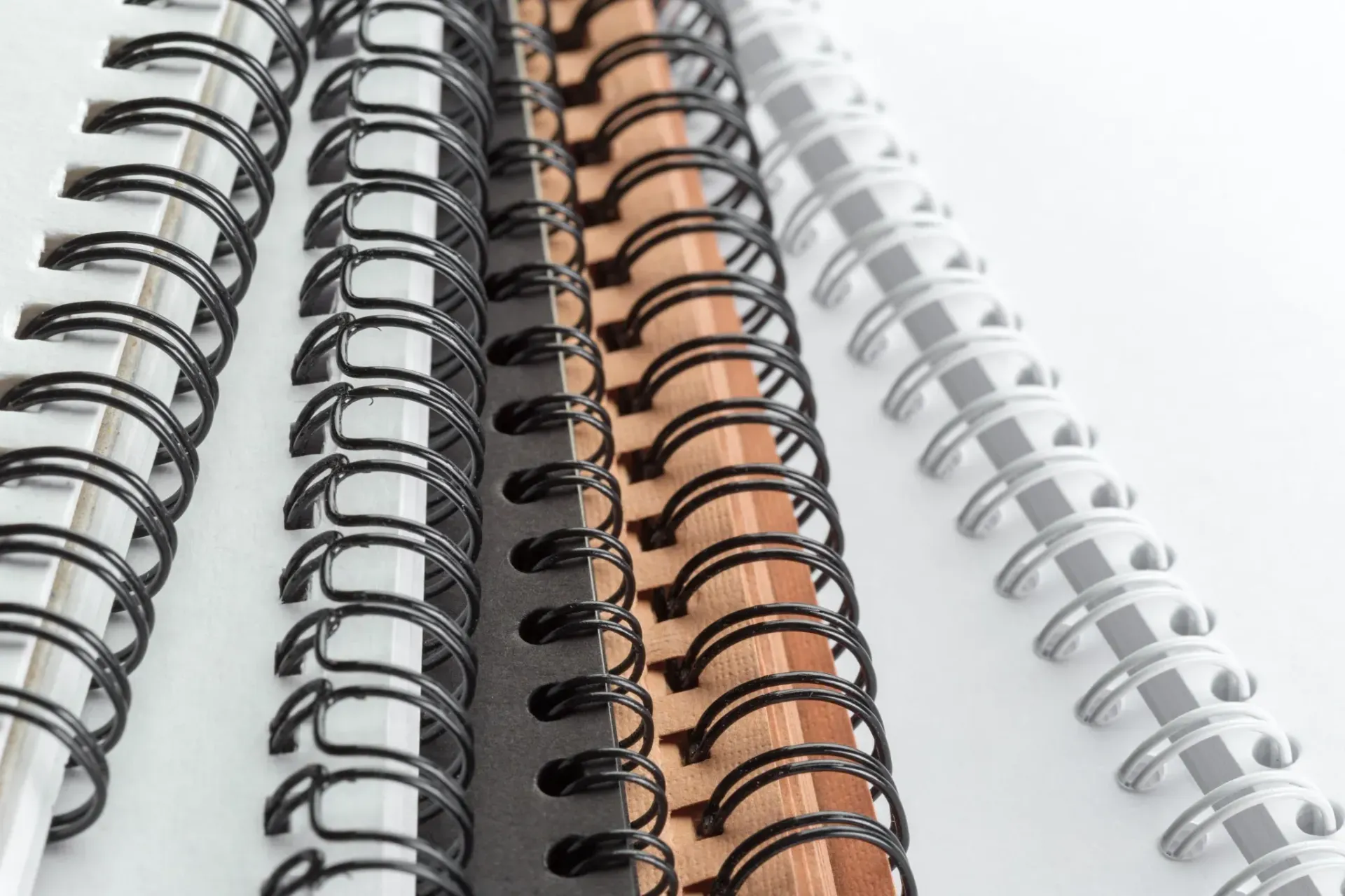 Cuadernos encuadernados en espiral en varios colores, dispuestos muy juntos.
