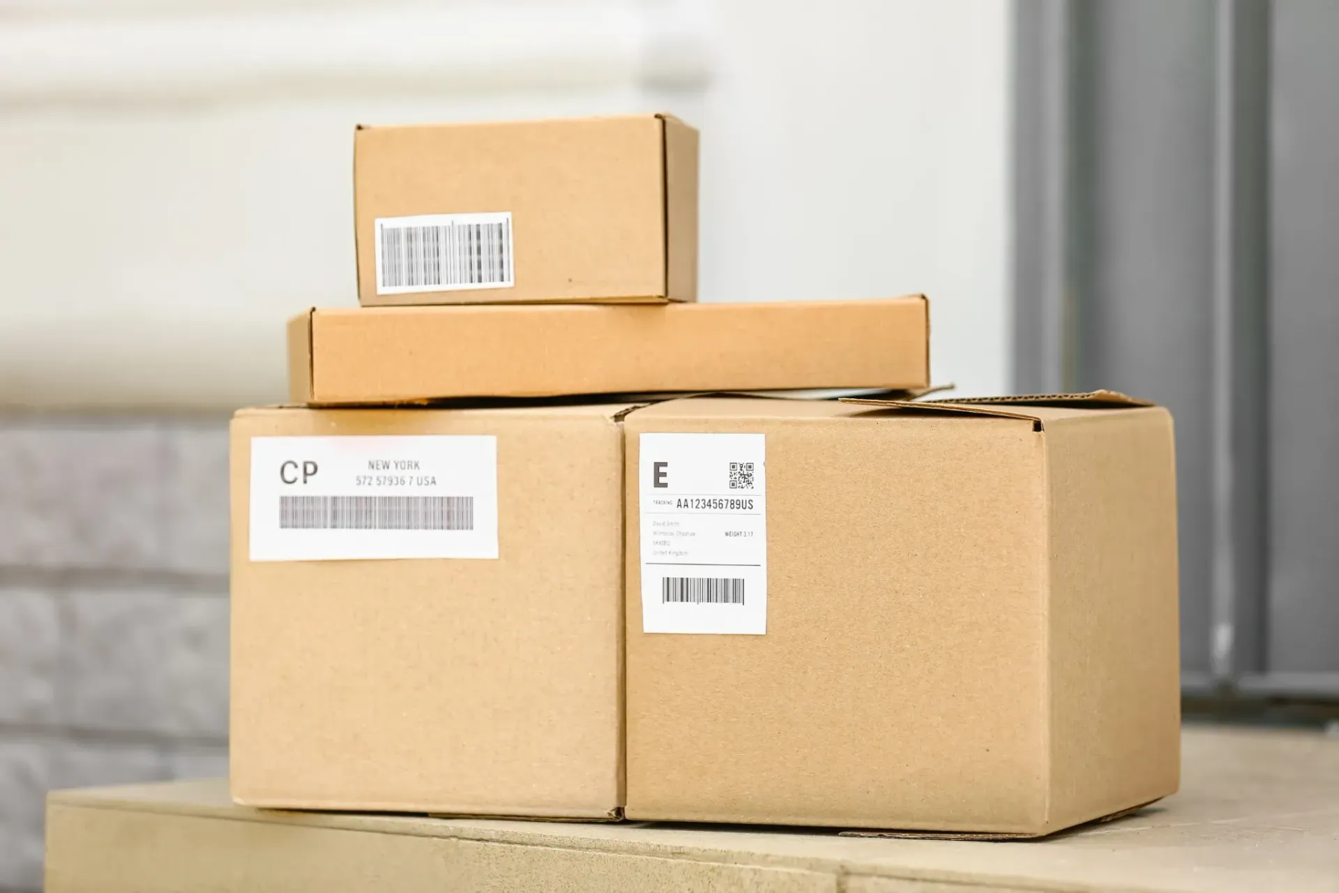 Paquetes de cartón apilados en un porche, listos para ser entregados.