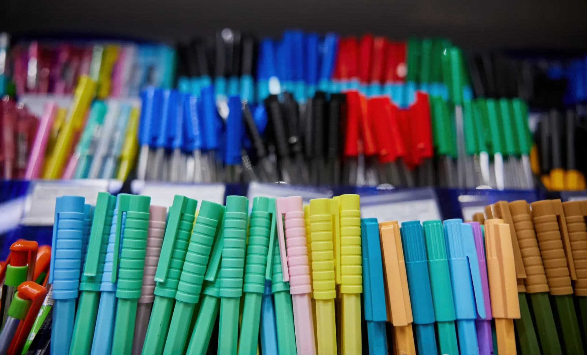 Filas de bolígrafos de colores en exhibición en una tienda.