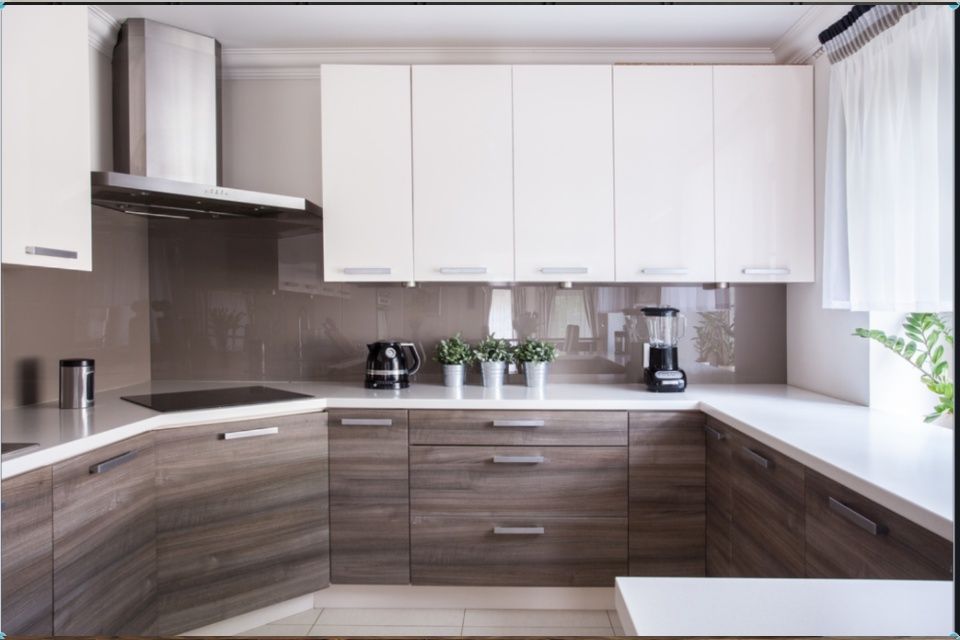 Moderni keittiö, jossa valkoiset yläkaapit, puunväriset alakaapistot ja valkoiset työtasot.