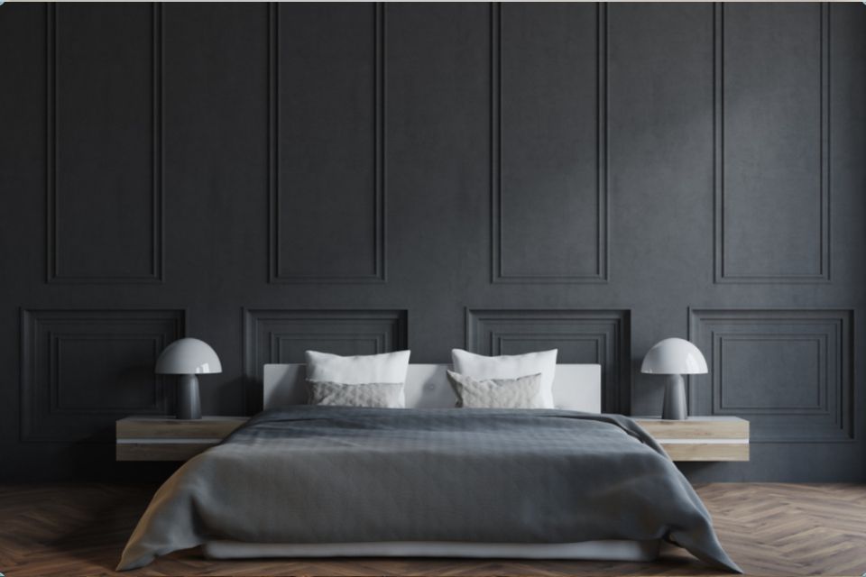 Tummanharmaa makuuhuone, jossa sänky, yhteensopivat seinäpaneelit ja kelluvat yöpöydät lampuineen.