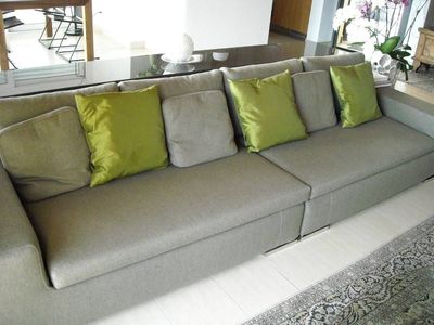 Divano grigio con cuscini verde lime in un luminoso soggiorno.