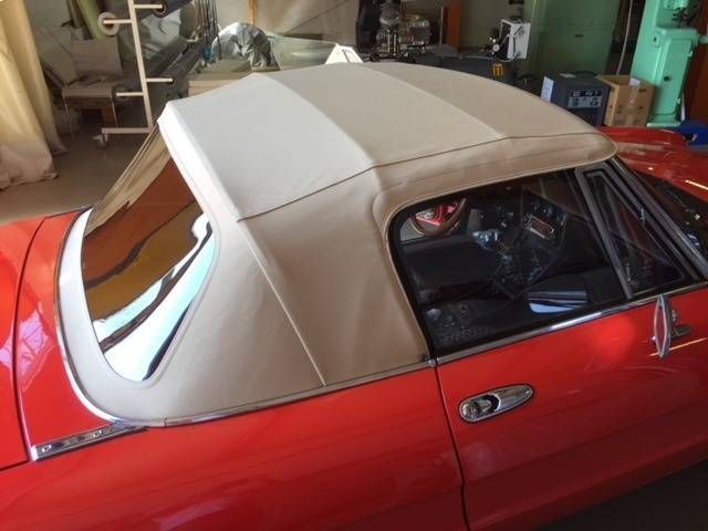 Auto rossa con capote beige in un garage