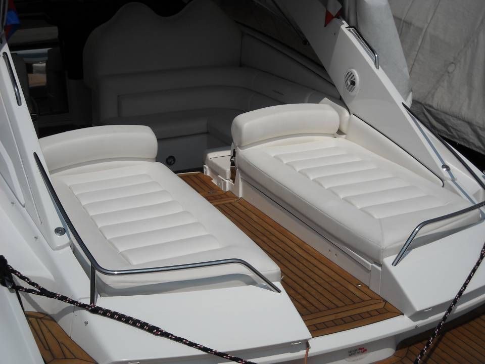 Due poltrone imbottite bianche sul ponte di una barca con una passerella centrale in teak.