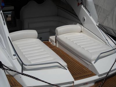 Due poltrone imbottite bianche sul ponte di una barca con una passerella centrale in teak.