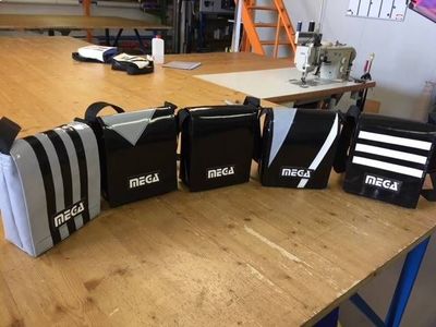 Sacchi neri MEGA allineati su un banco da lavoro in legno in un'officina.