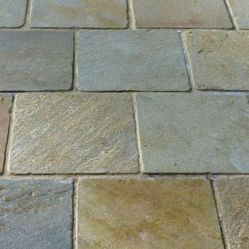 Gros plan sur des dalles de pavage en pierre grise et beige avec des carreaux rectangulaires irréguliers