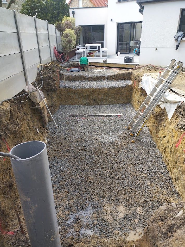 Cour arrière excavée avec une base de gravier, des murs de soutènement et une échelle appuyée contre la fosse.