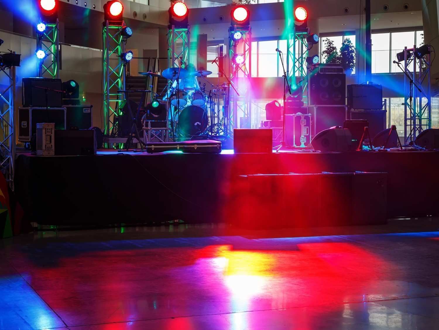 Montaje del escenario con instrumentos musicales, equipos de audio y luces de escenario de colores rojo, azul.