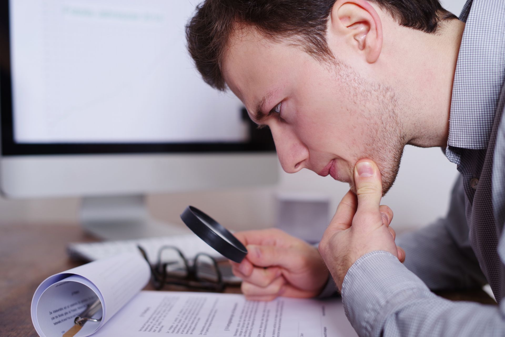 Homme utilisant une loupe pour lire un document