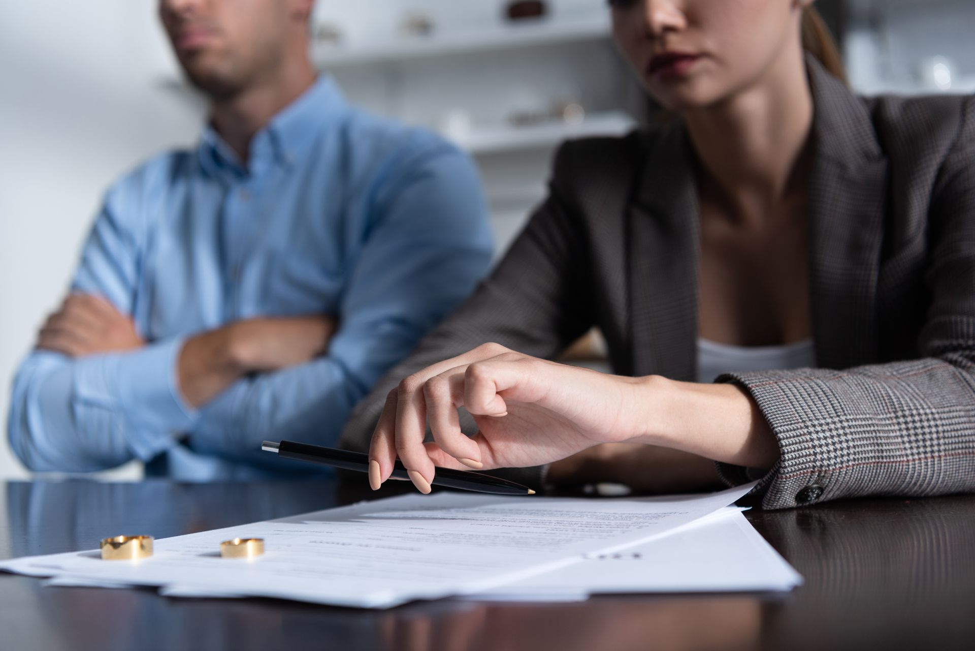 Homme croisant les bras et femme tenant un stylo pour signer un document