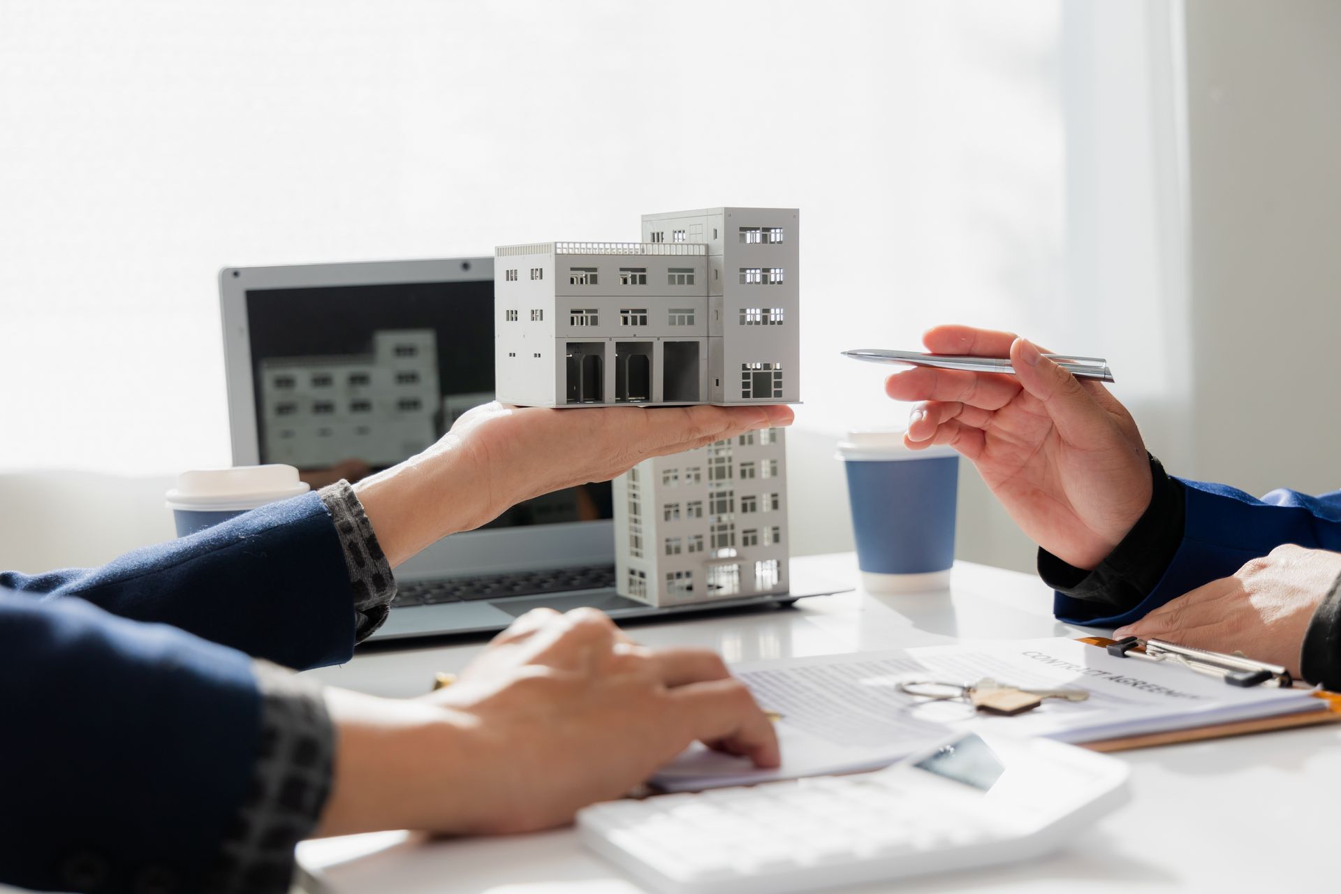 Mains tenant une maquette d'immeubles