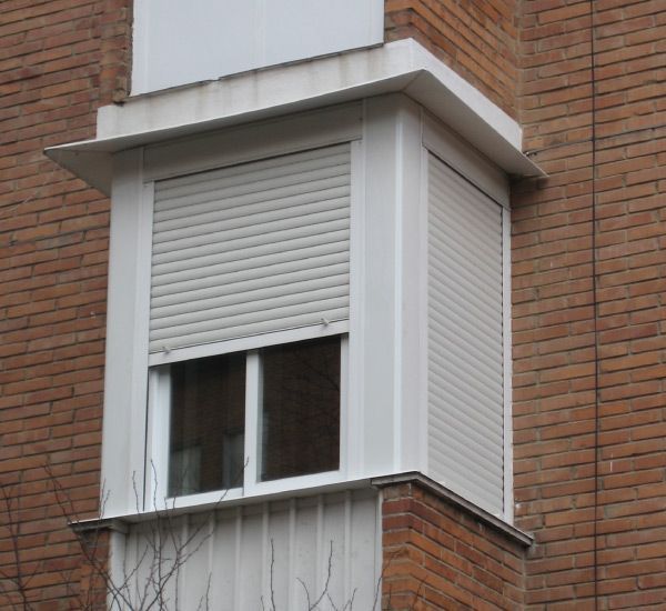 Un edificio de ladrillo con una ventana con contraventanas.