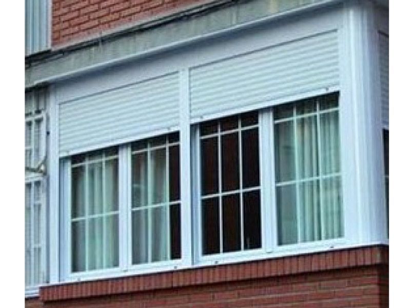 Una ventana blanca con contraventanas en un edificio de ladrillo.