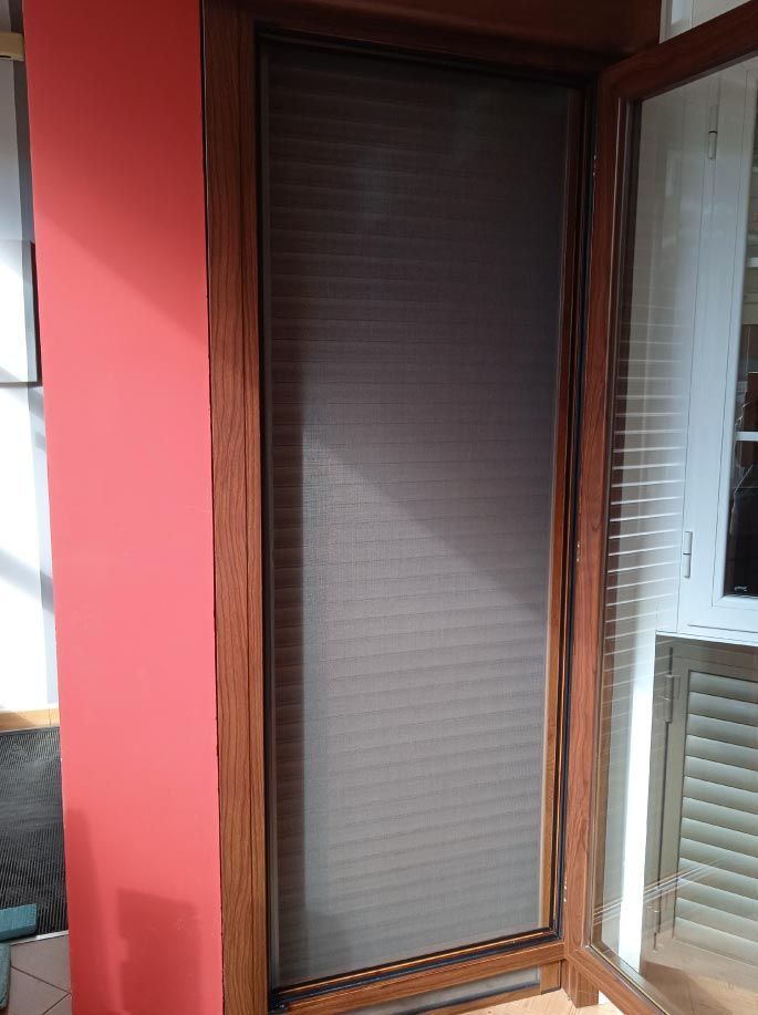 Una puerta con una mampara y una pared roja detrás.