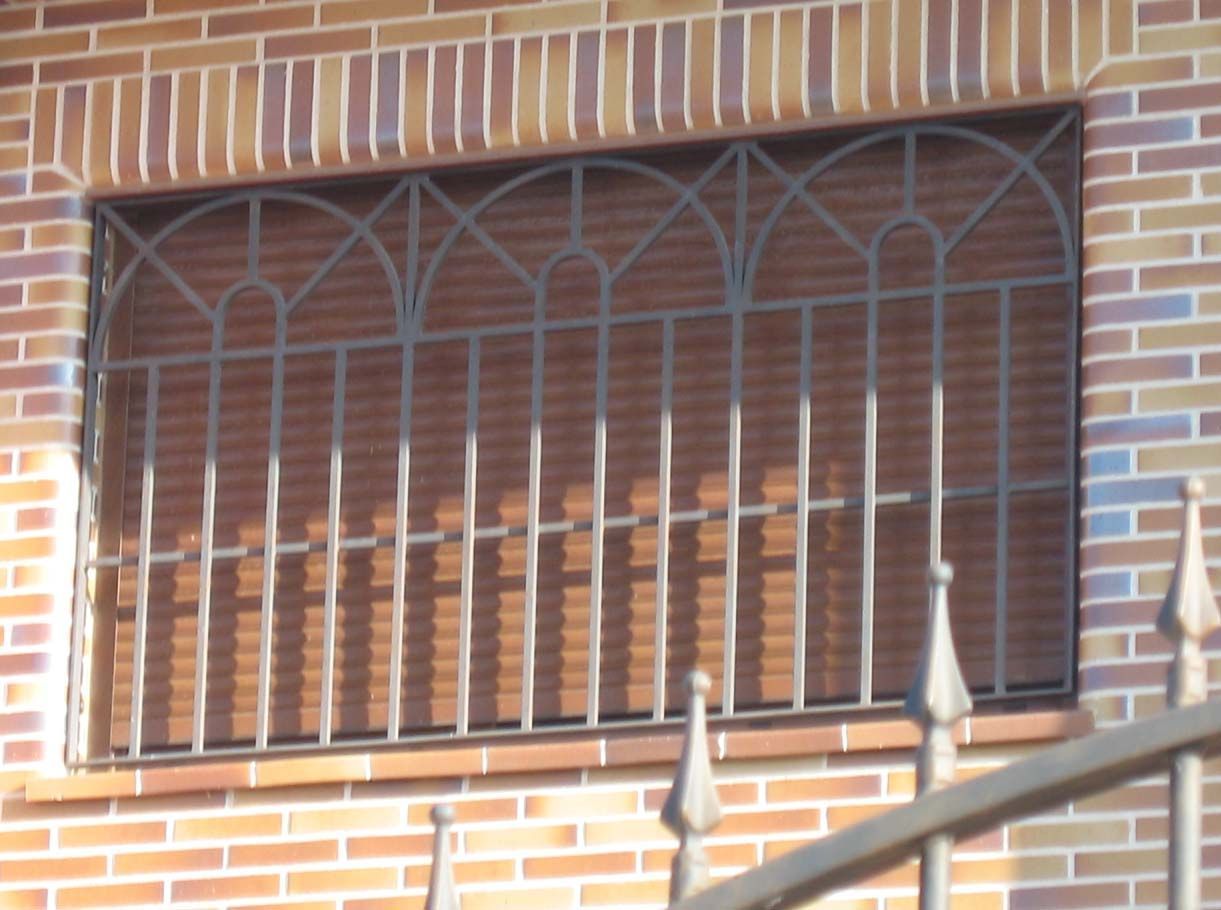 Un edificio de ladrillo con una ventana con una valla de hierro forjado alrededor.