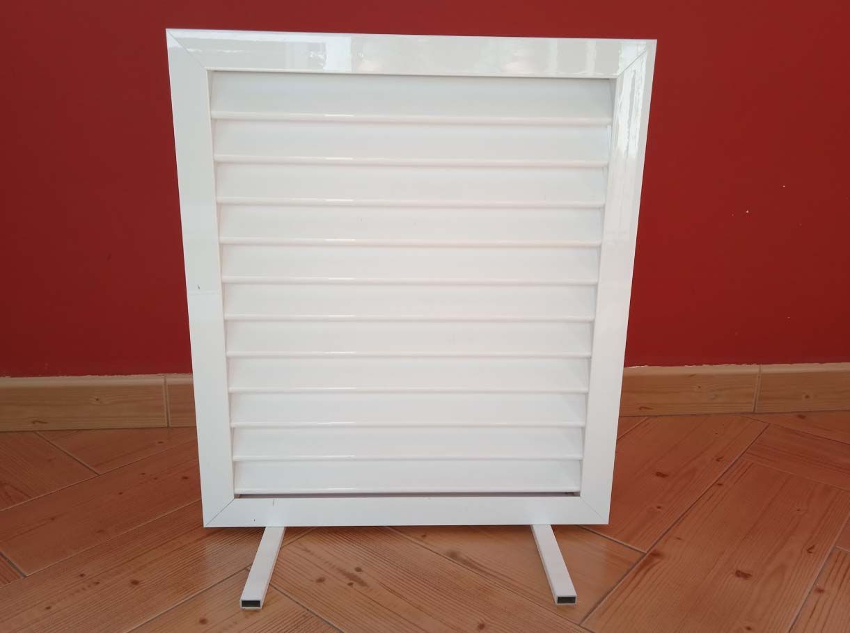 Una caja blanca está sobre un piso de madera frente a una pared roja.
