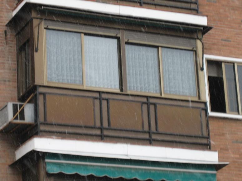 Un balcón en un edificio de ladrillo con un toldo verde.