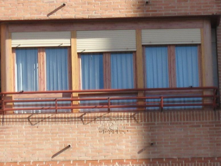 Un edificio de ladrillo con tres ventanas y un balcón.