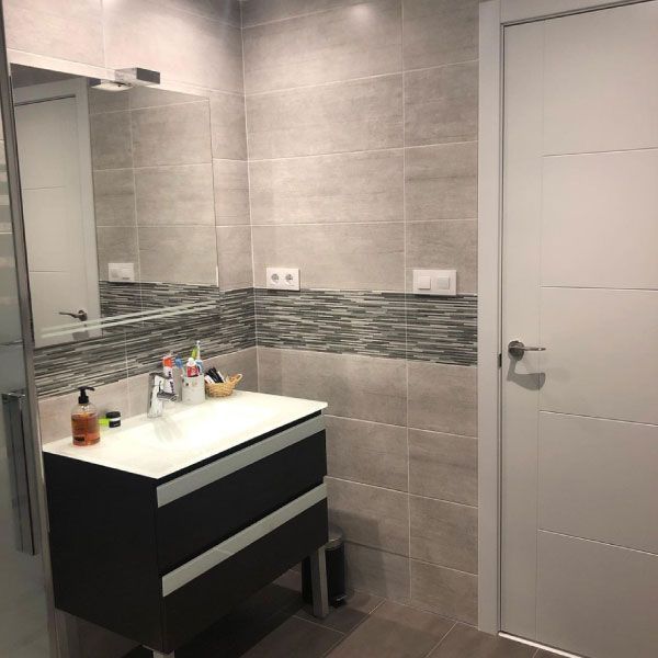 Un baño con lavabo, espejo y puerta.