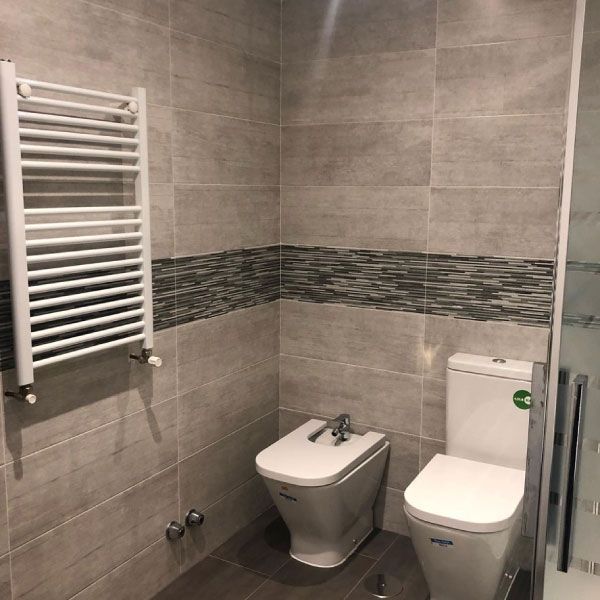Un baño con inodoro y bidé y toallero.