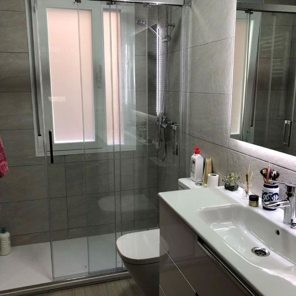 Un baño con inodoro, lavabo, ducha y espejo.