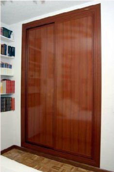 Un dormitorio con puertas corredizas de madera y estantes con libros en ellos.