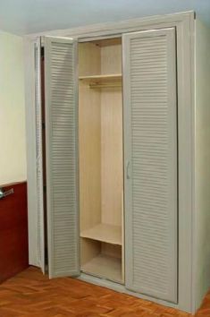 Un armario blanco con puertas tipo persiana en un dormitorio.