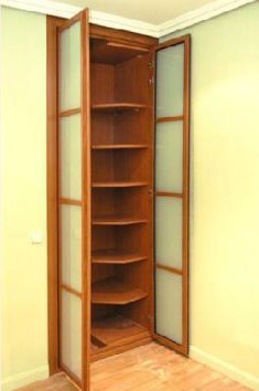 Un armario de madera con puertas de cristal y estantes en una habitación.