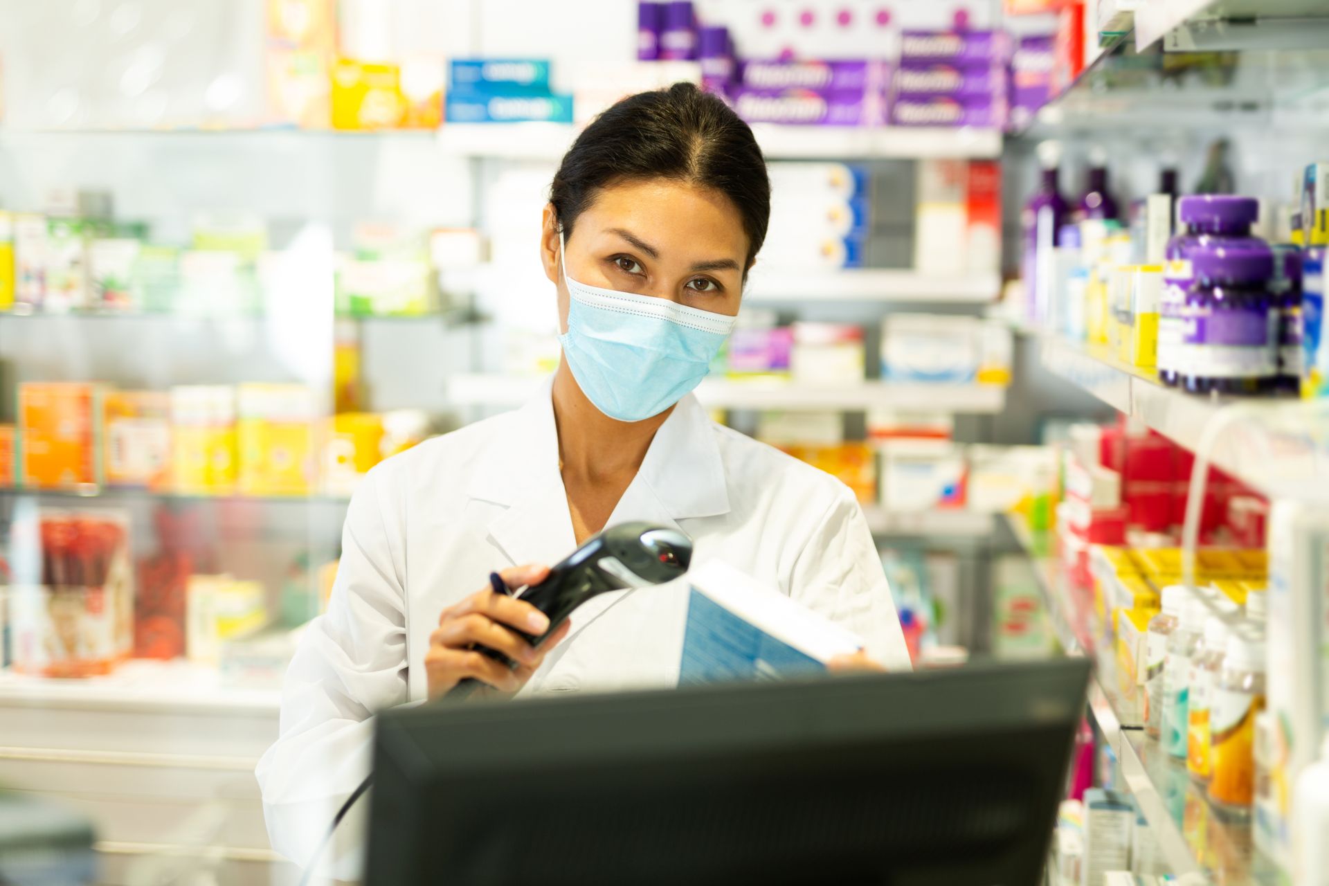 Femme avec un masque et une blouse devant une caisse enregistreuse