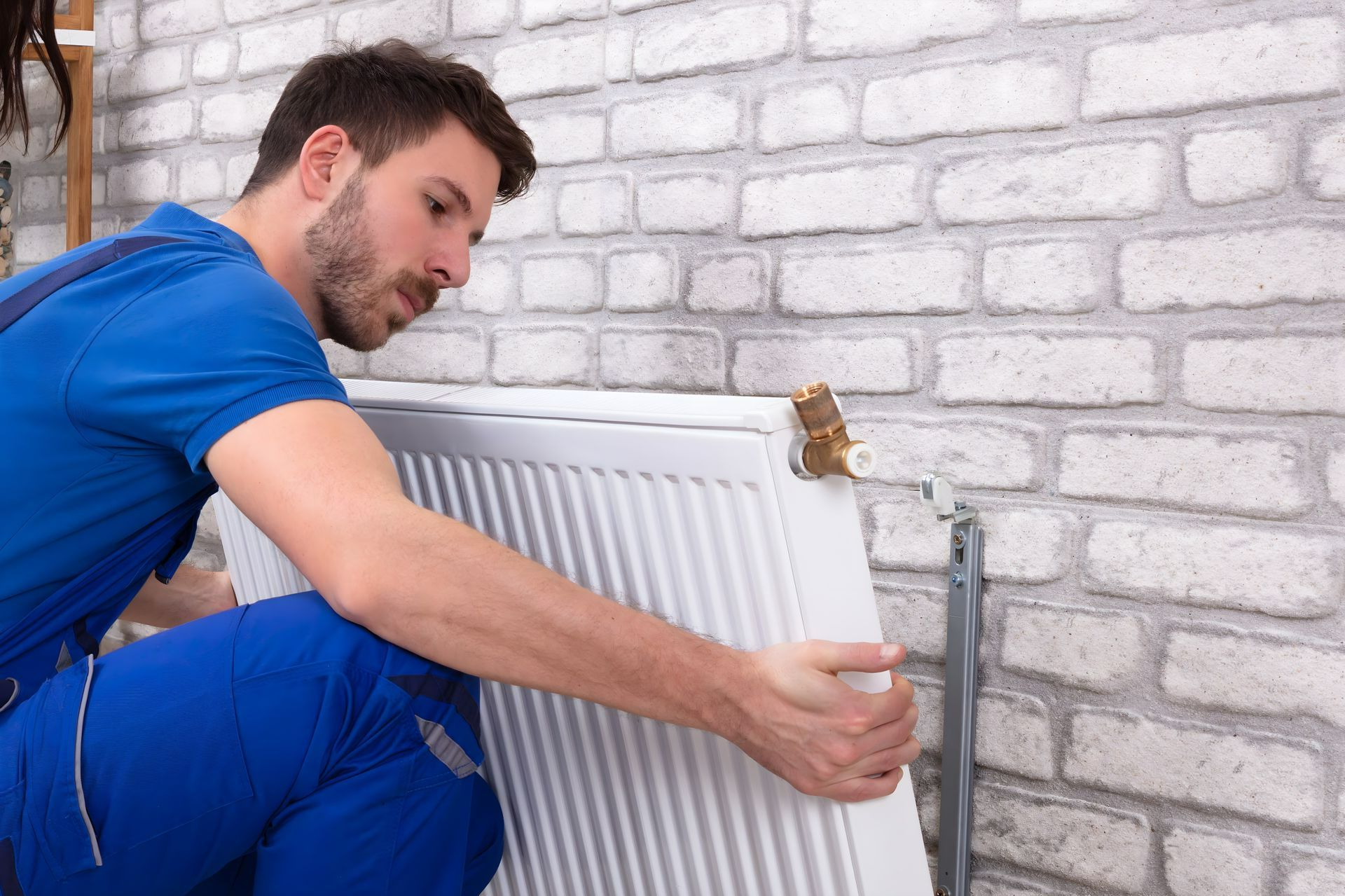 Un artisan installe un radiateur