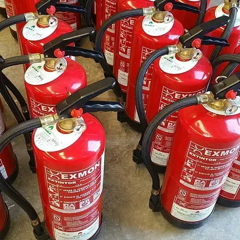 Un montón de extintores rojos están alineados en el suelo.
