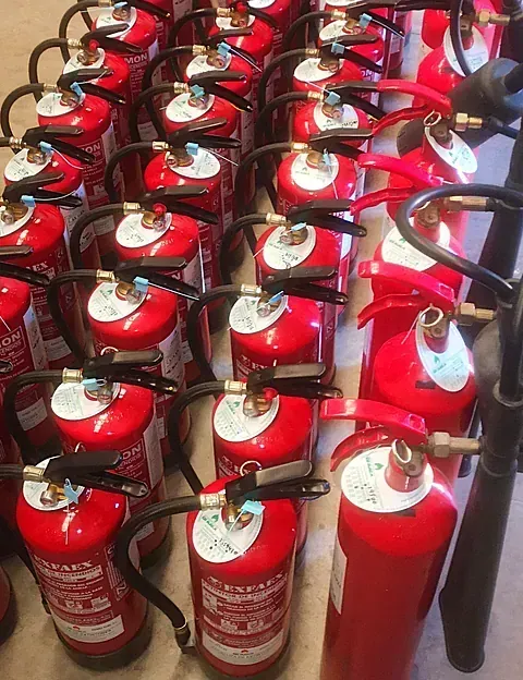 Una fila de extintores rojos están alineados en una fila.