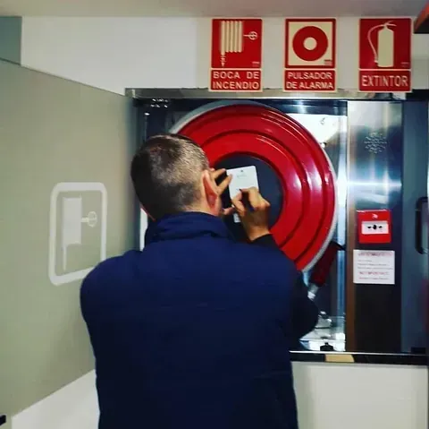 Un hombre está parado frente a un extintor de incendios.