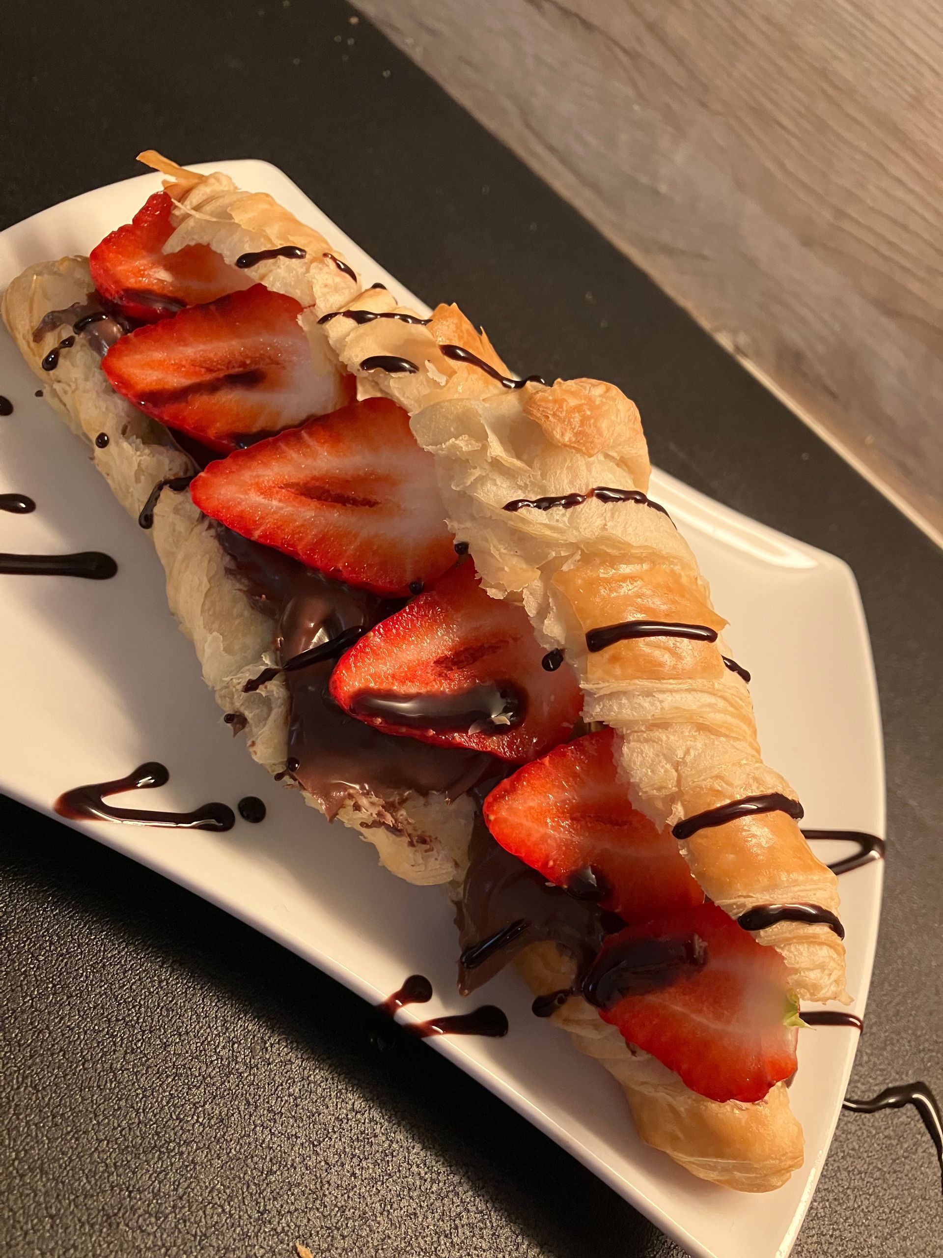 Ein Sandwich mit Erdbeeren und Schokoladensauce auf einem weißen Teller