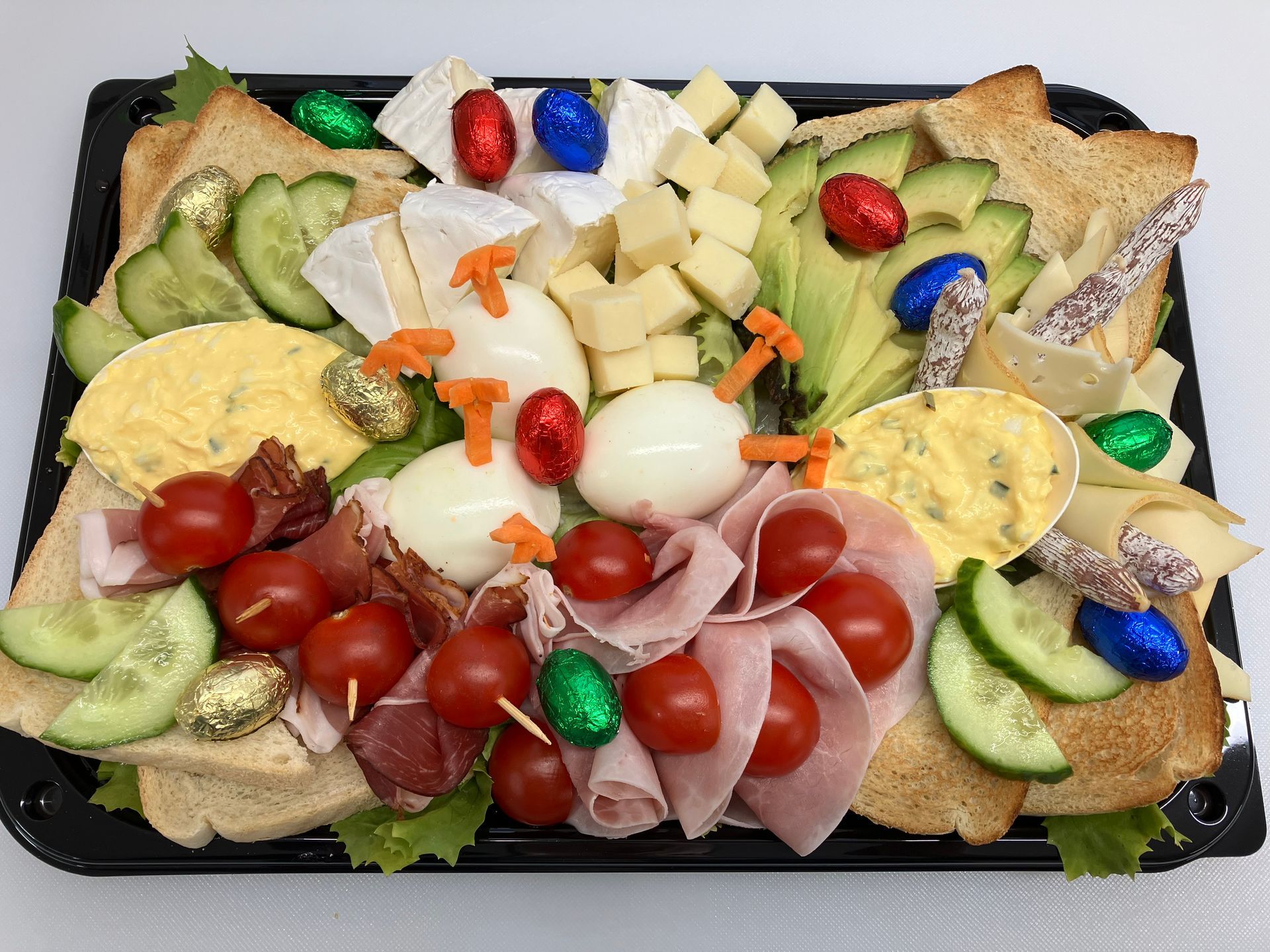 Ein Tablett mit Eiern, Schinken, Käse, Tomaten, Gurken und Avocado.