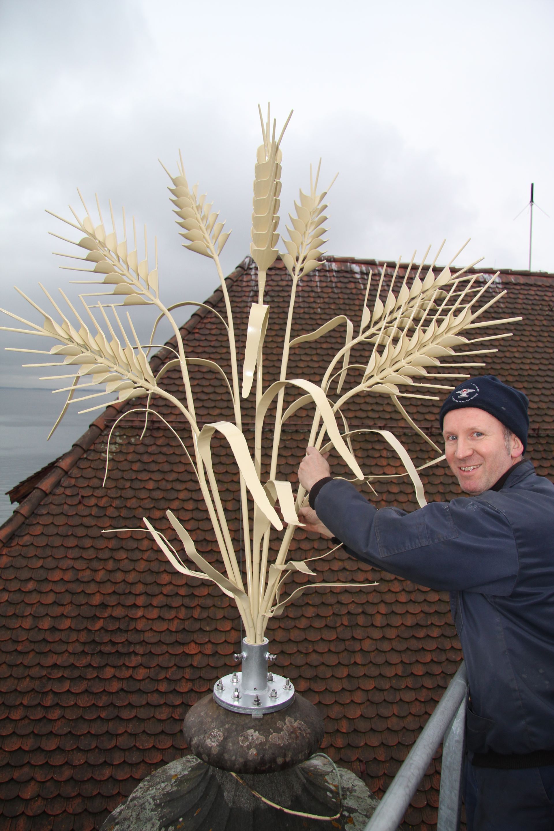 Ein Schmied, der in seiner Werkstatt mit einem Lufthammer einen glühend roten Metallstab formt, trägt Schutzausrüstung.