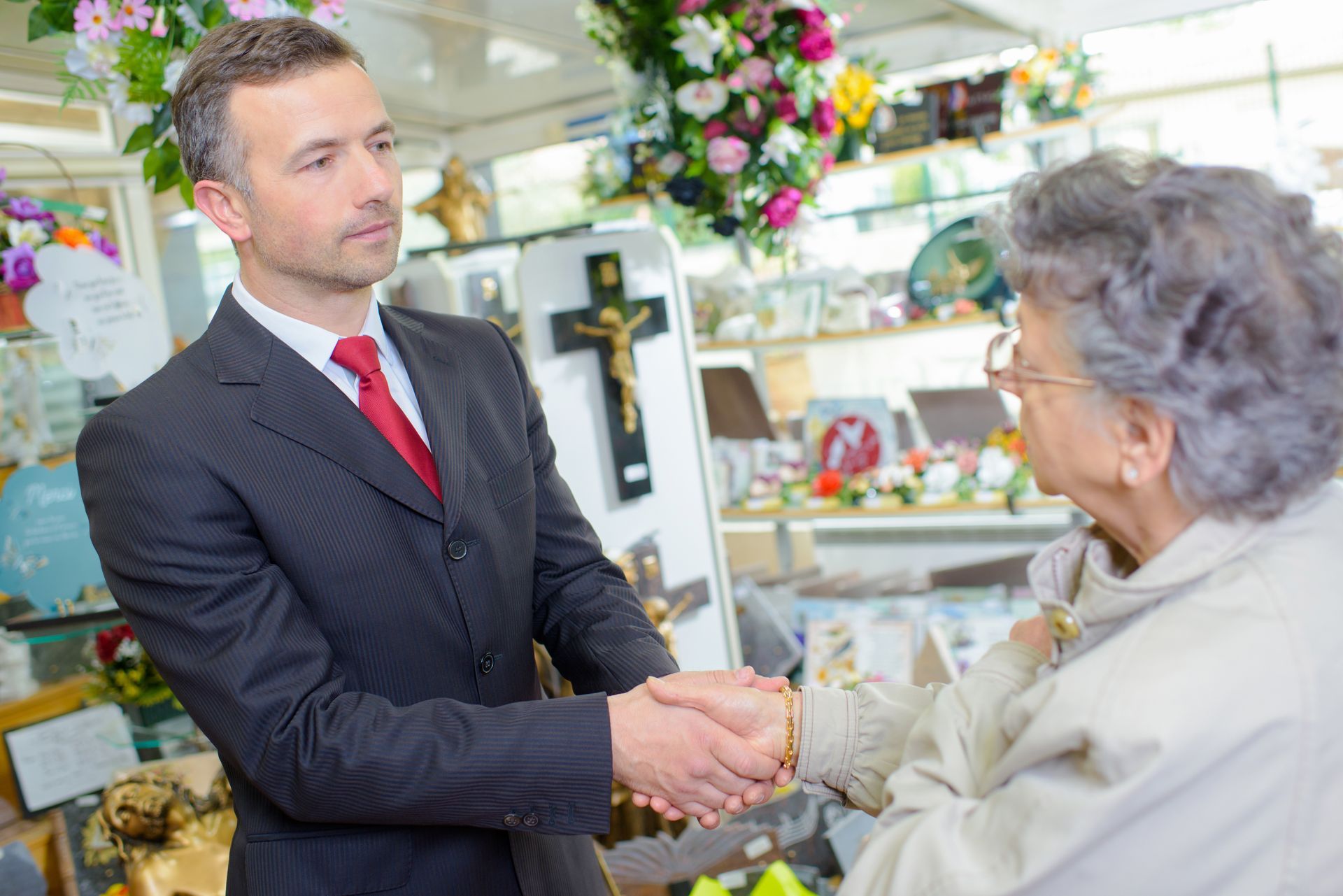 Un homme en costume serrant la main d'une cliente âgée