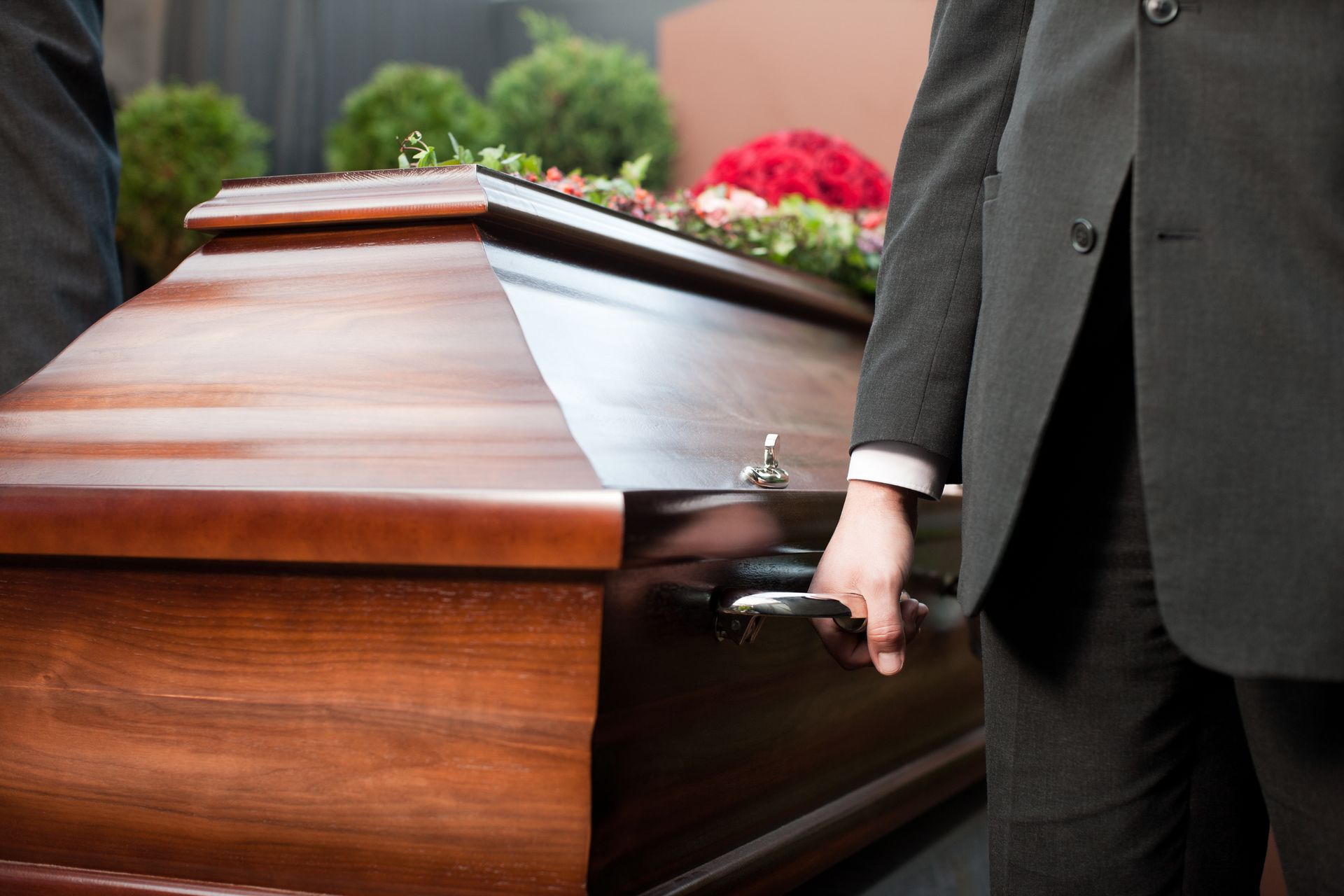 Un homme tenant la poignée d'un cercueil en bois