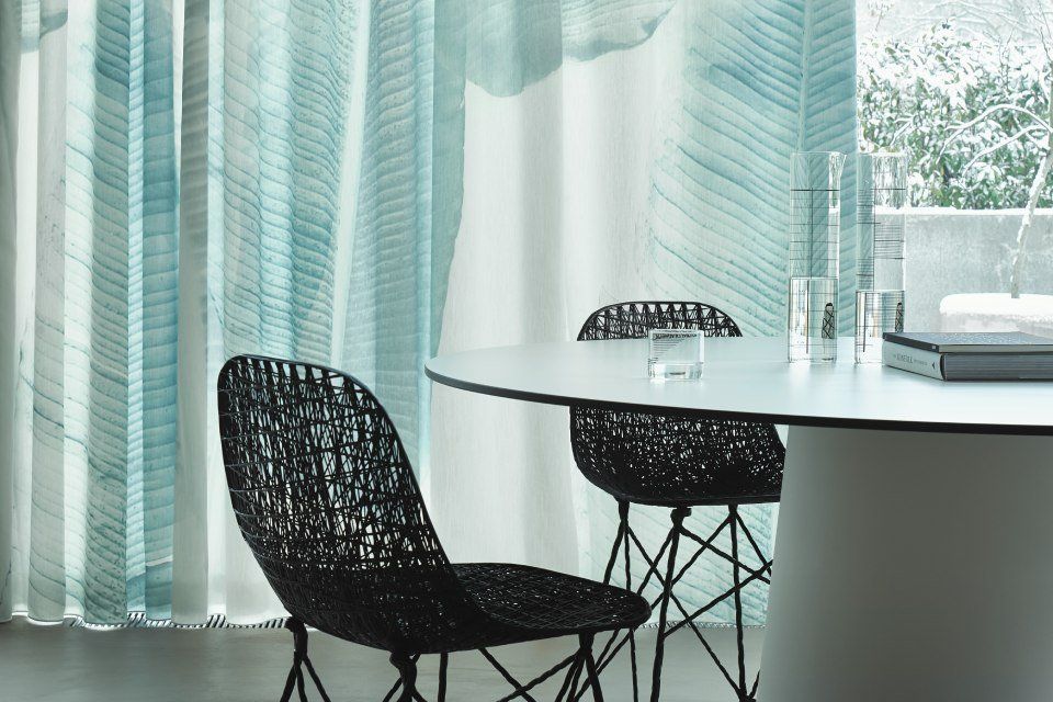 Ein Esszimmer mit einem Tisch und Stühlen vor einem Fenster.