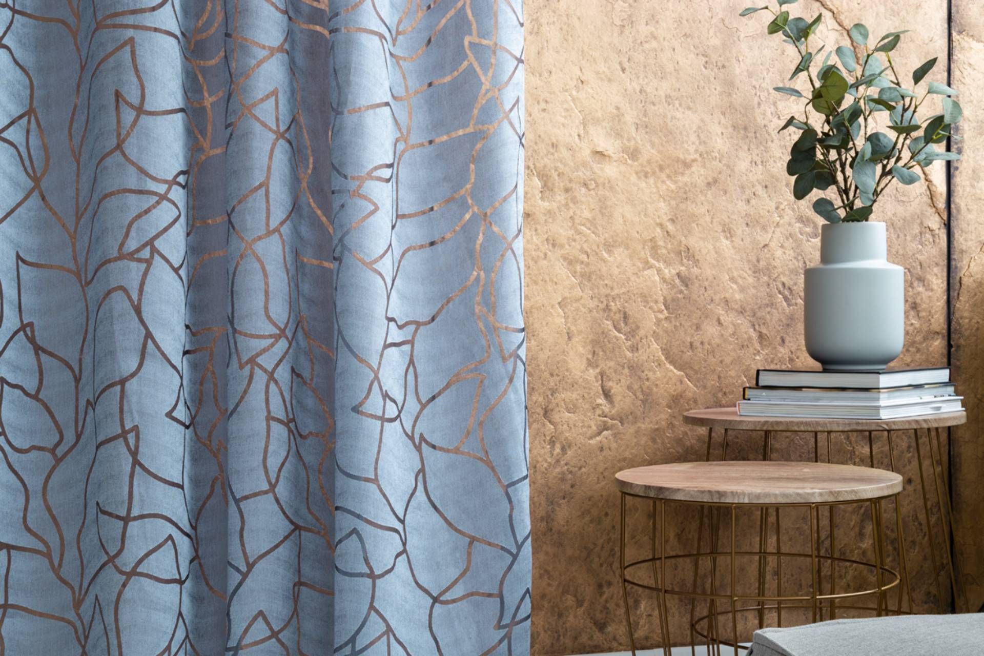 Ein Wohnzimmer mit einem blauen Vorhang und einer Pflanze auf einem Tisch.