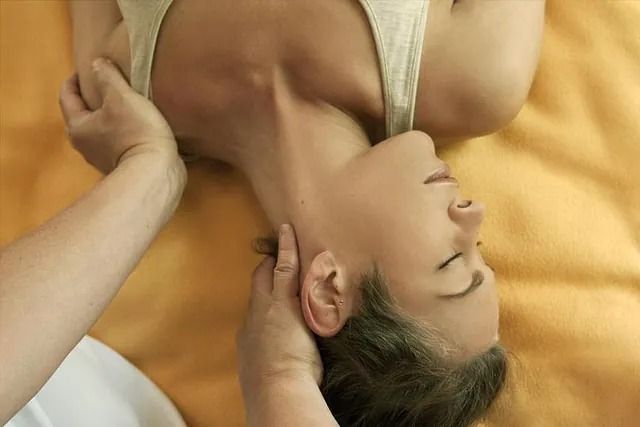 Una mujer está acostada en una cama recibiendo un masaje de cuello.