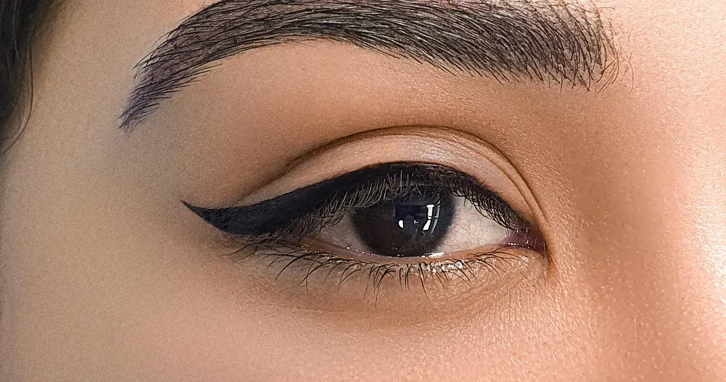 Un primer plano del ojo de una mujer con delineador de ojos y cejas.