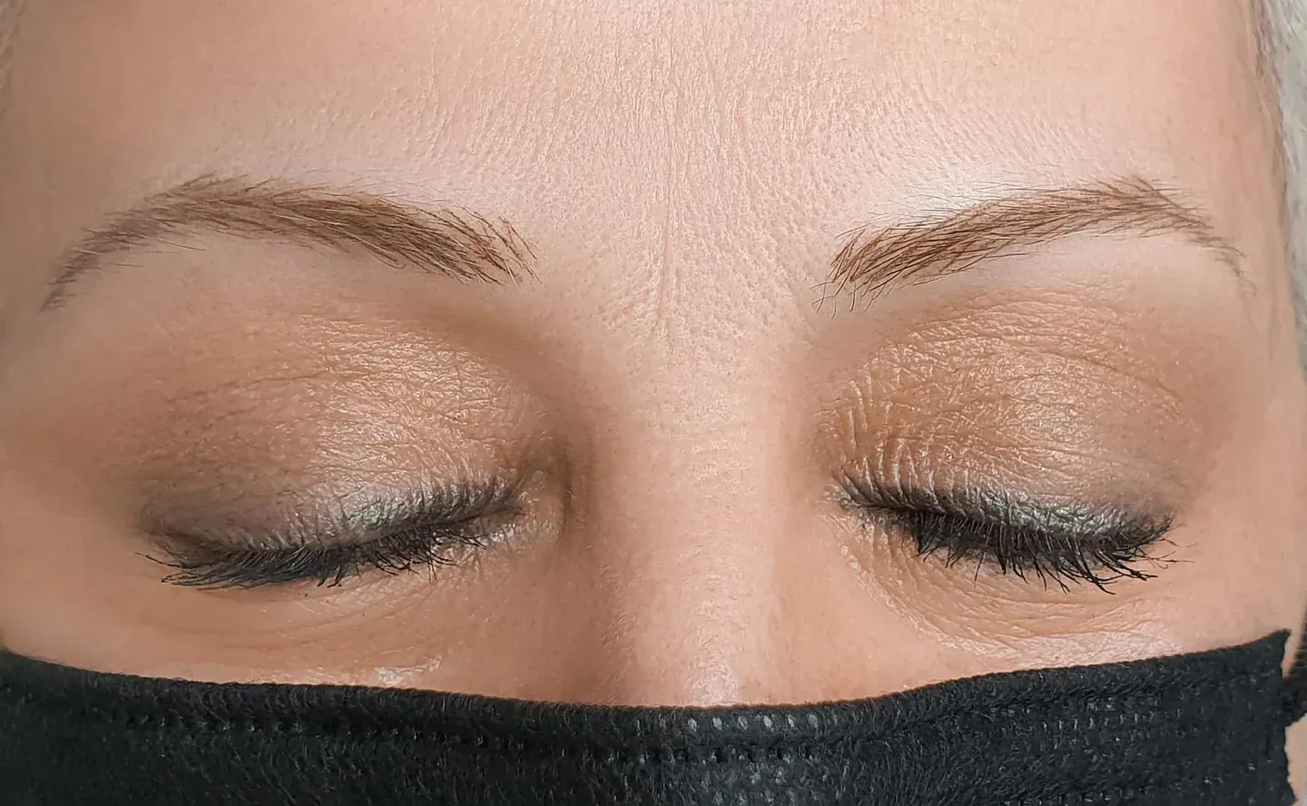 Un primer plano de una mujer que lleva una máscara con los ojos cerrados.