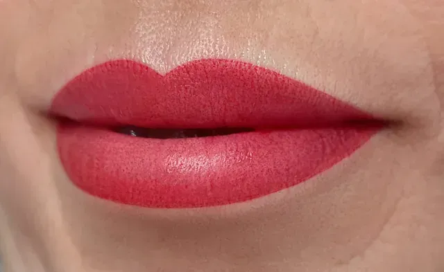 Un primer plano de los labios de una mujer con lápiz labial rojo.