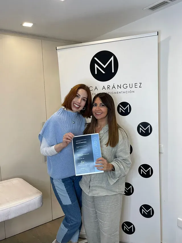 Dos mujeres están paradas una al lado de la otra en una habitación sosteniendo un libro.