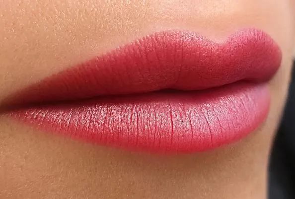 Un primer plano de los labios de una mujer con lápiz labial rojo.