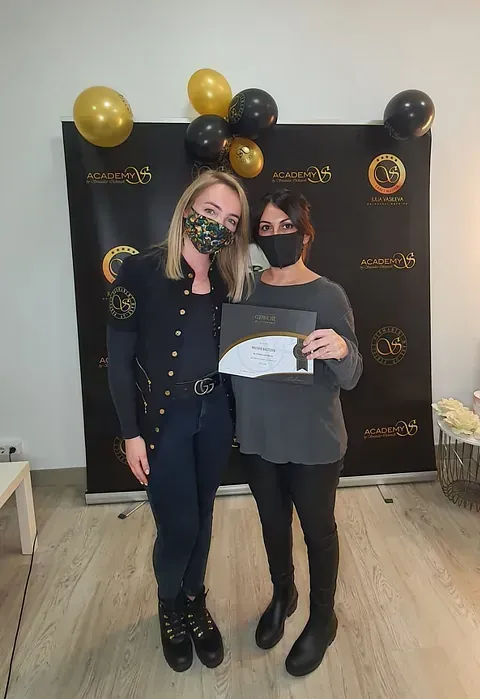 Dos mujeres con máscaras están paradas una al lado de la otra frente a una pared con globos.
