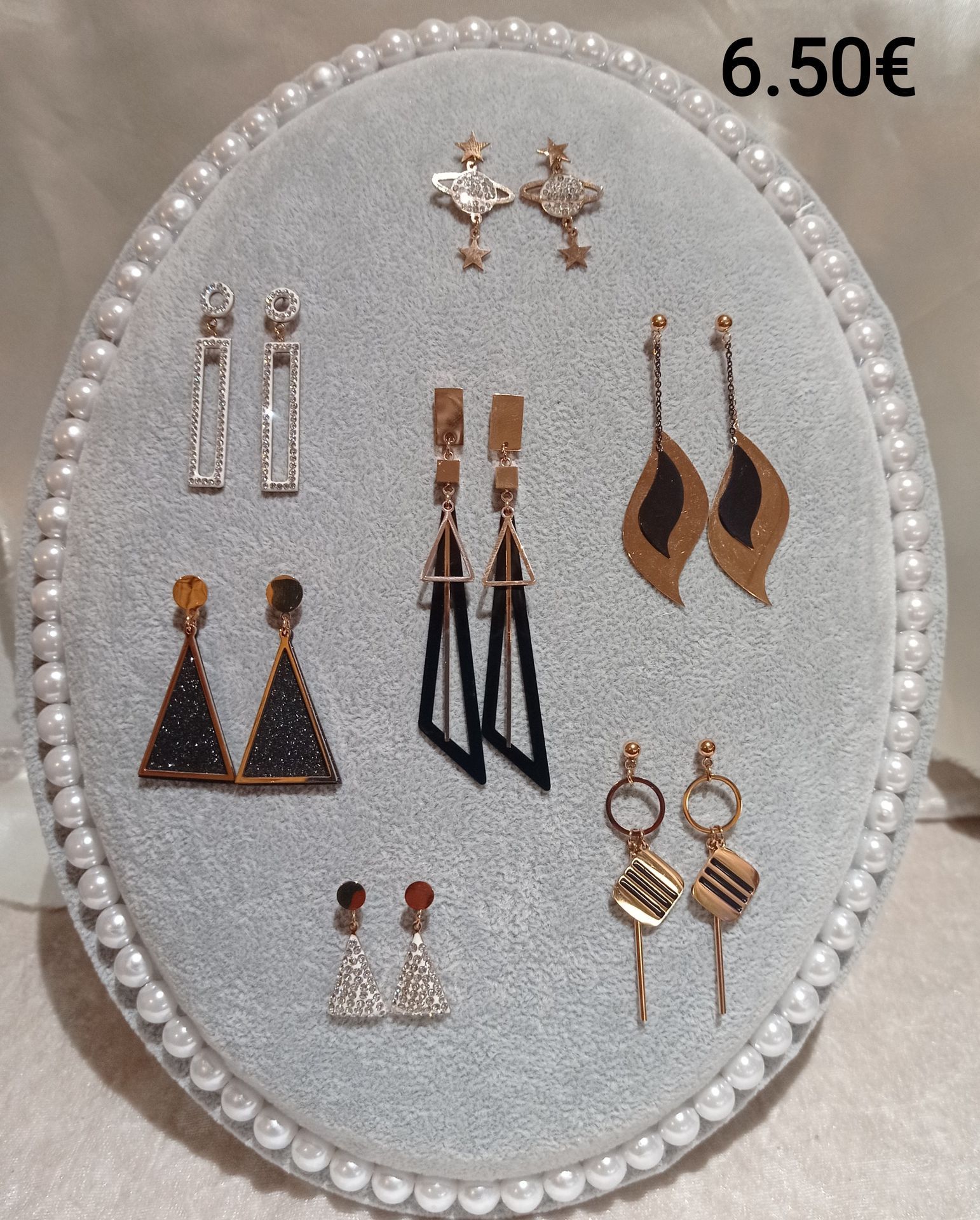 Plusieurs lots de boucles d'oreilles pendantes sur un socle en tissu.