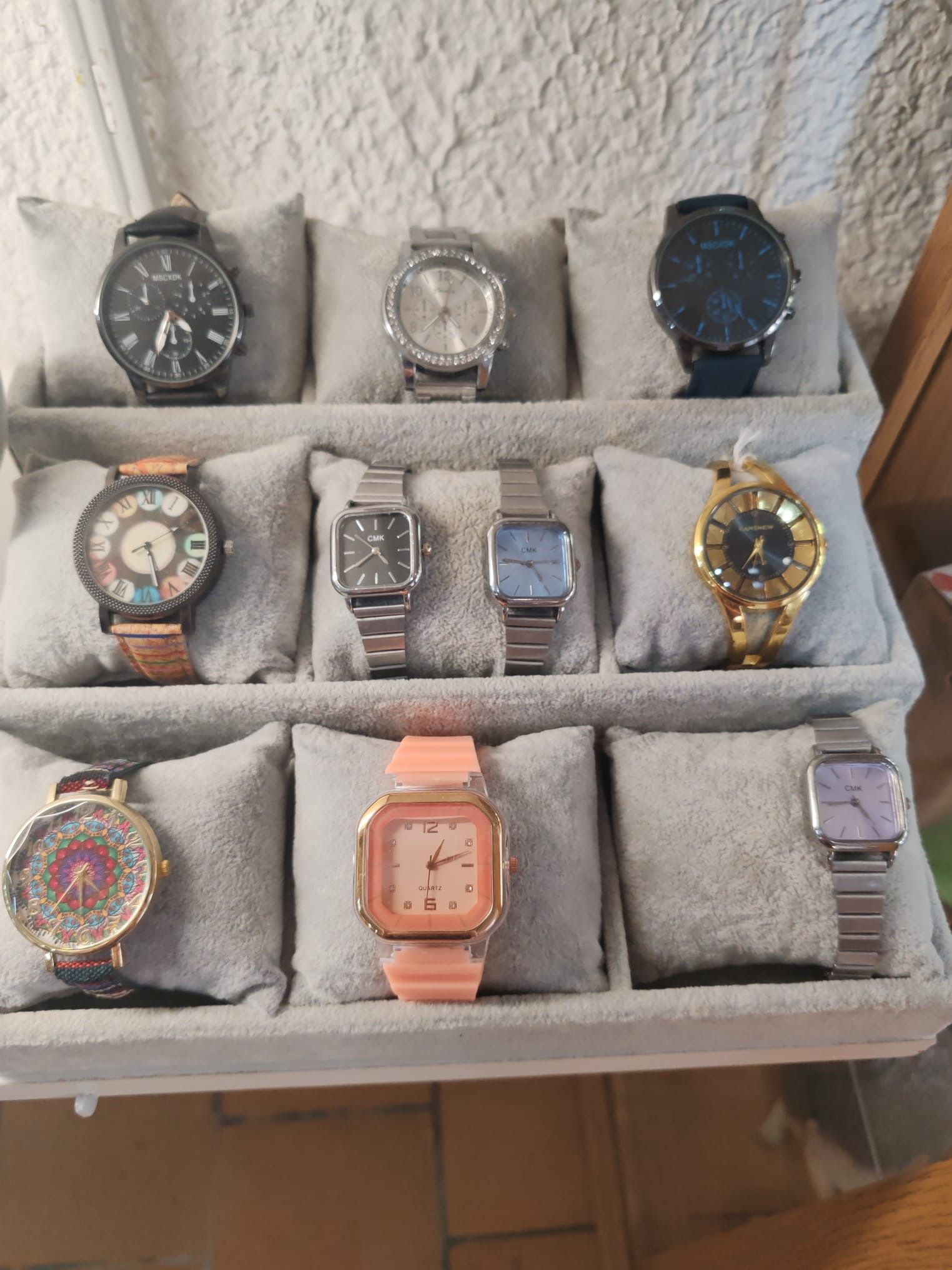 Montres assorties disposées dans un plateau de présentation gris sur des coussins en tissu.